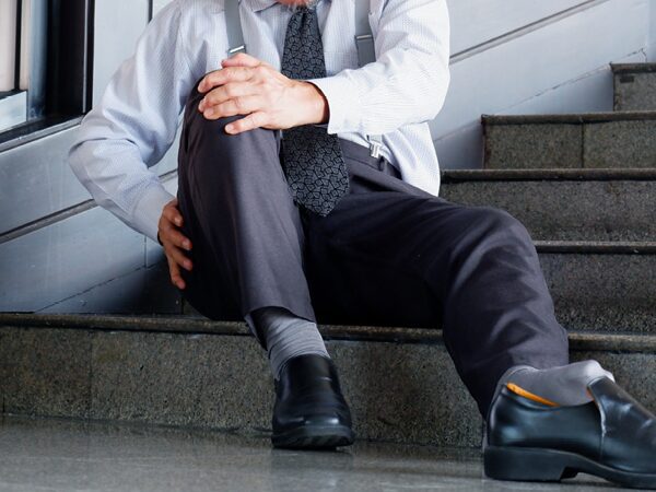 Man holding his knee at the bottom of a staircase